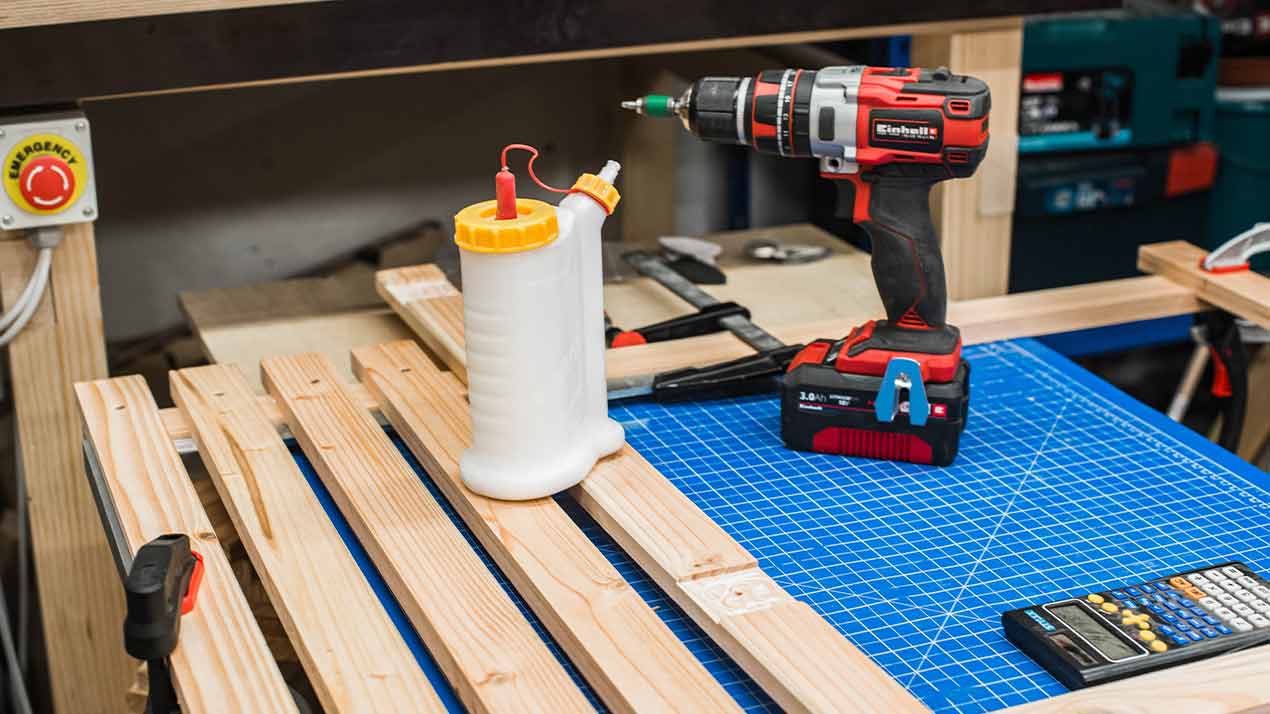 Wood glue and cordless screwdriver are standing on a workbench