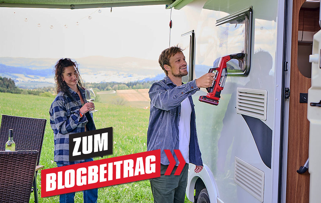 Ein Mann reinigt das Fenster eines Wohnmobils mit dem Einhell BRILLIANTO, während eine Frau daneben steht und ein Glas Wein hält; im Vordergrund steht die Beschriftung "Zum Blogbeitrag".