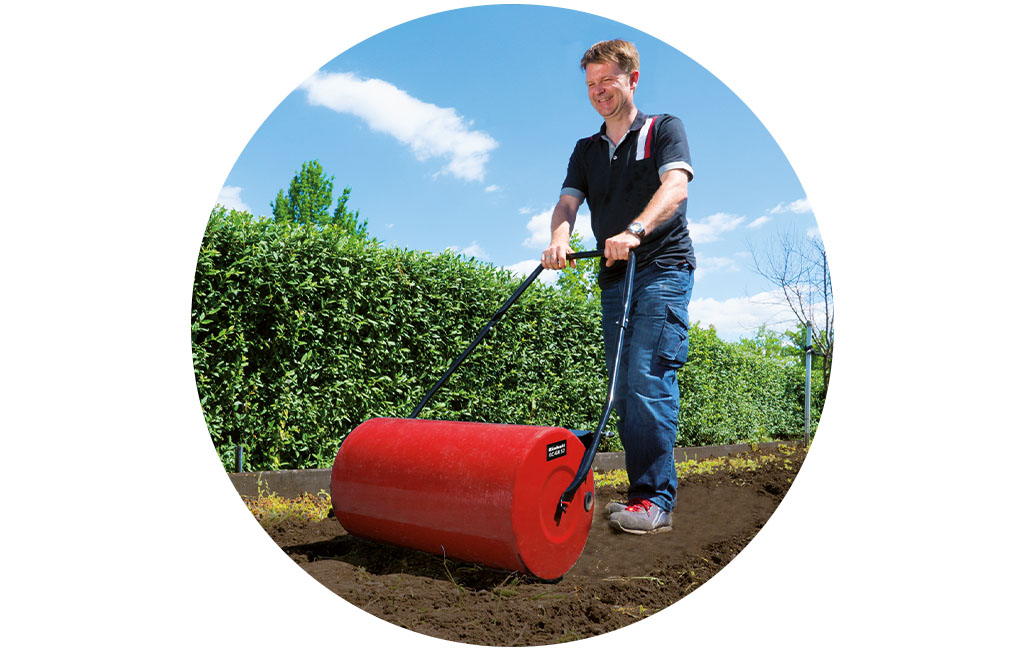 a man rolls the ground with the Einhell Garden Roller