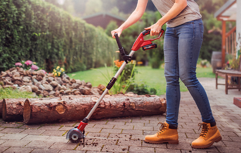 a woman is cleaning grout with the Einhell cordless grout cleaner