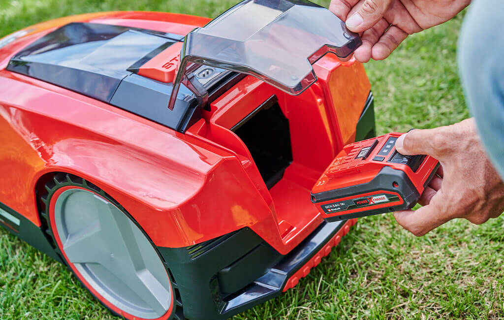 A Power X-Change battery is inserted into an Einhell Freelexo robotic lawnmower.