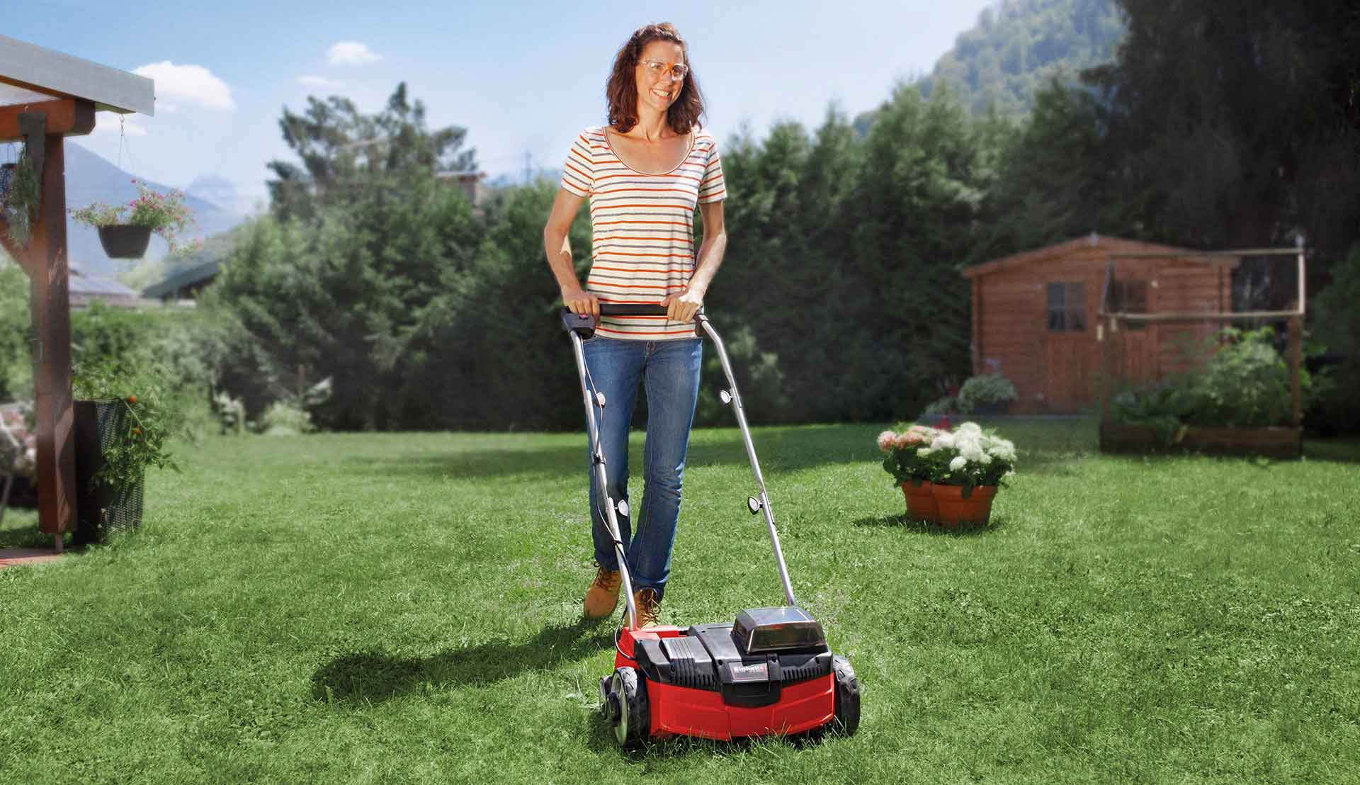 The woman is scarifying the lawn in her garden