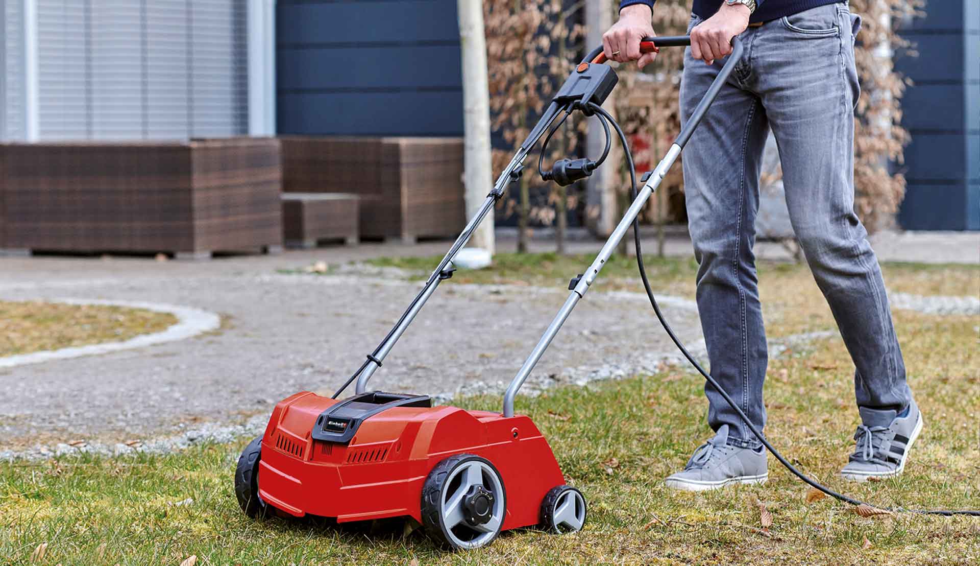 A man is scarifying the lawn in a garden