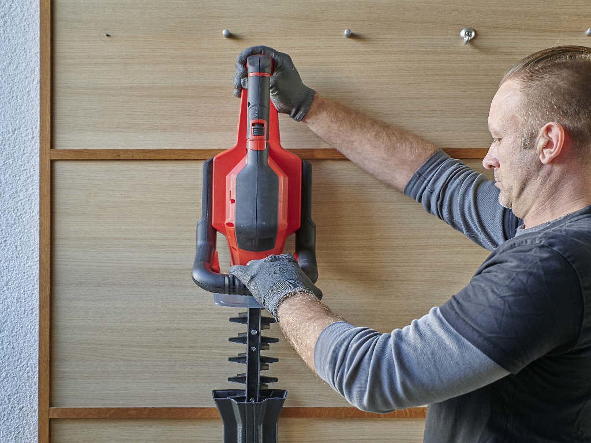 A man stores a hedge trimmer.