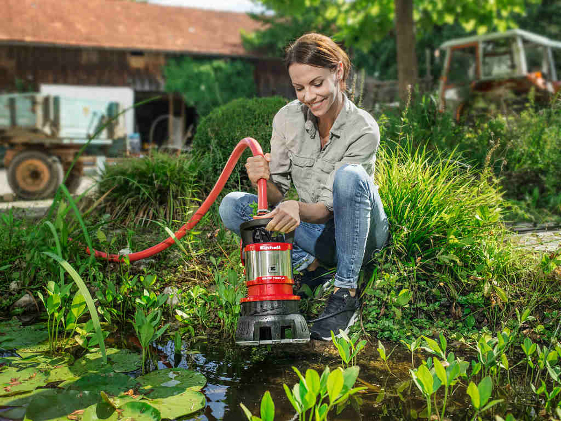 A woman removes a garden pump of a pond.