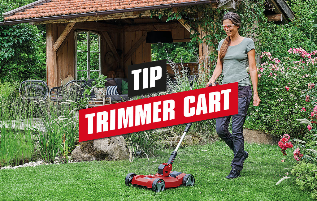 a woman is mowing the lawn with a Einhell cordless lawn trimmer with its trimmer cart