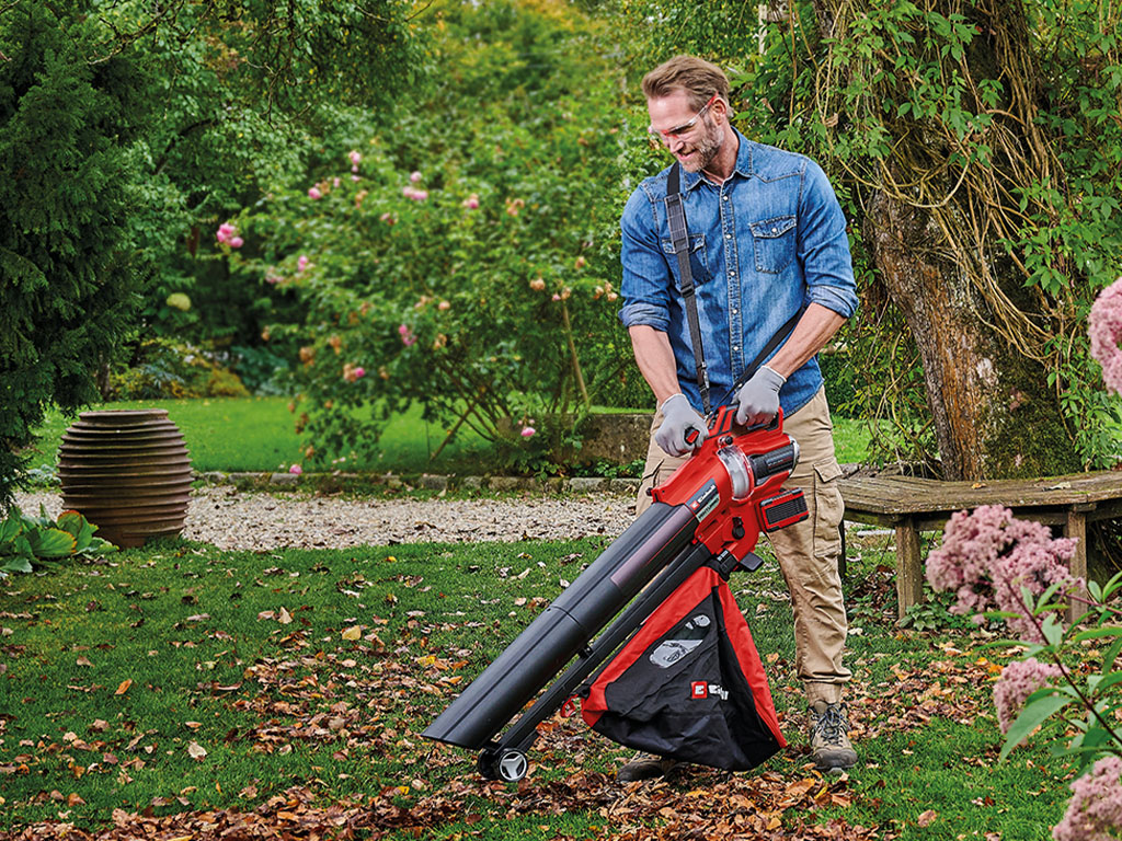 ein Mann nutzt einen Einhell Akku-Laubsauger in einem Garten