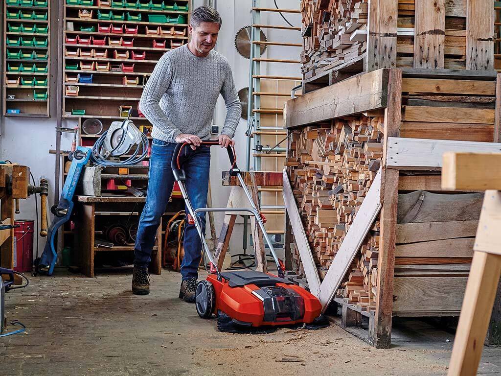 a man cleans his workshop with a sweeper