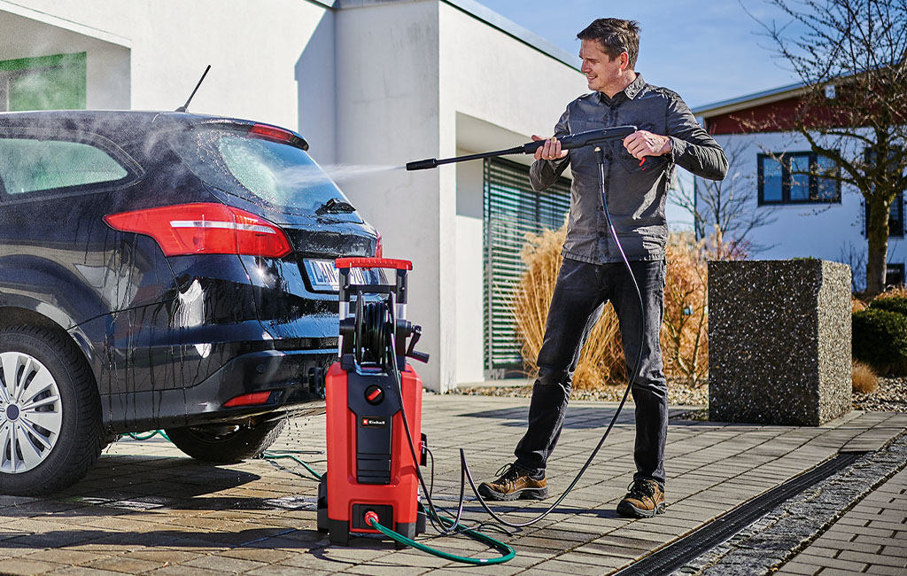 A man cleans a car with a Einhell high pressure cleaner