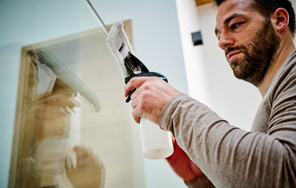 Man cleans windows glass with the Einhell BRILLIANTO