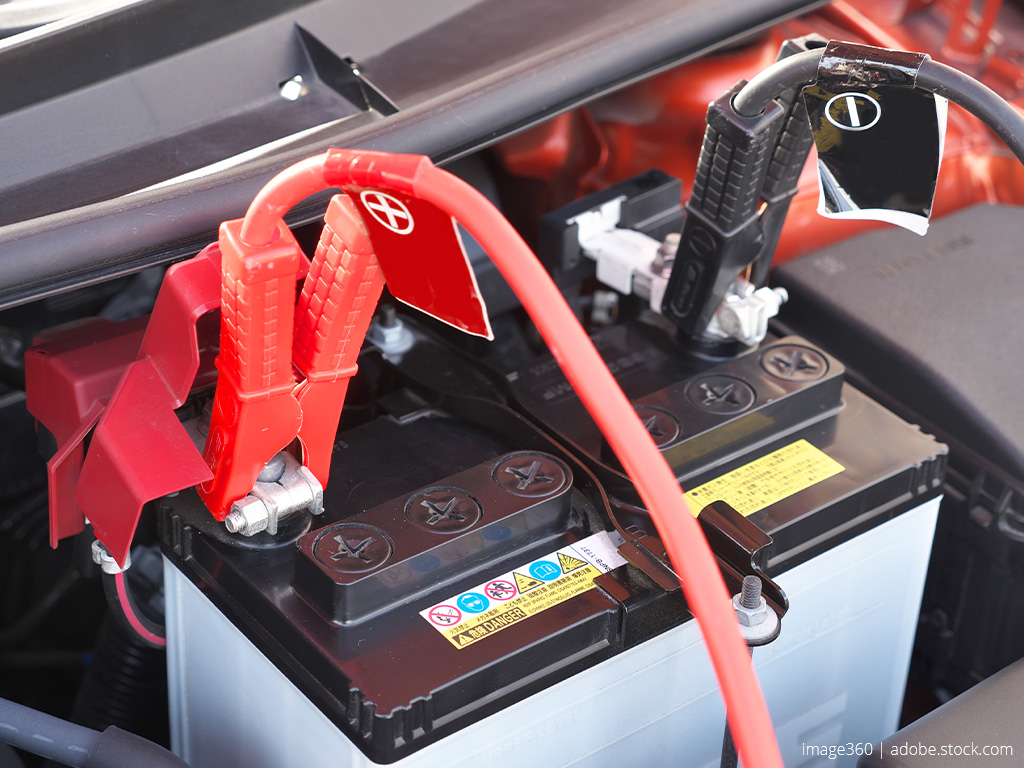 Car battery connected to a red cable at the positive terminal and a black cable at the negative terminal.