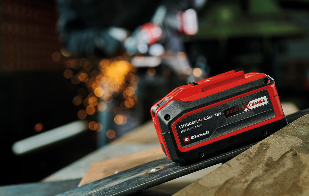 The Einhell Multi-Ah battery is placed on a workbench in a workshop