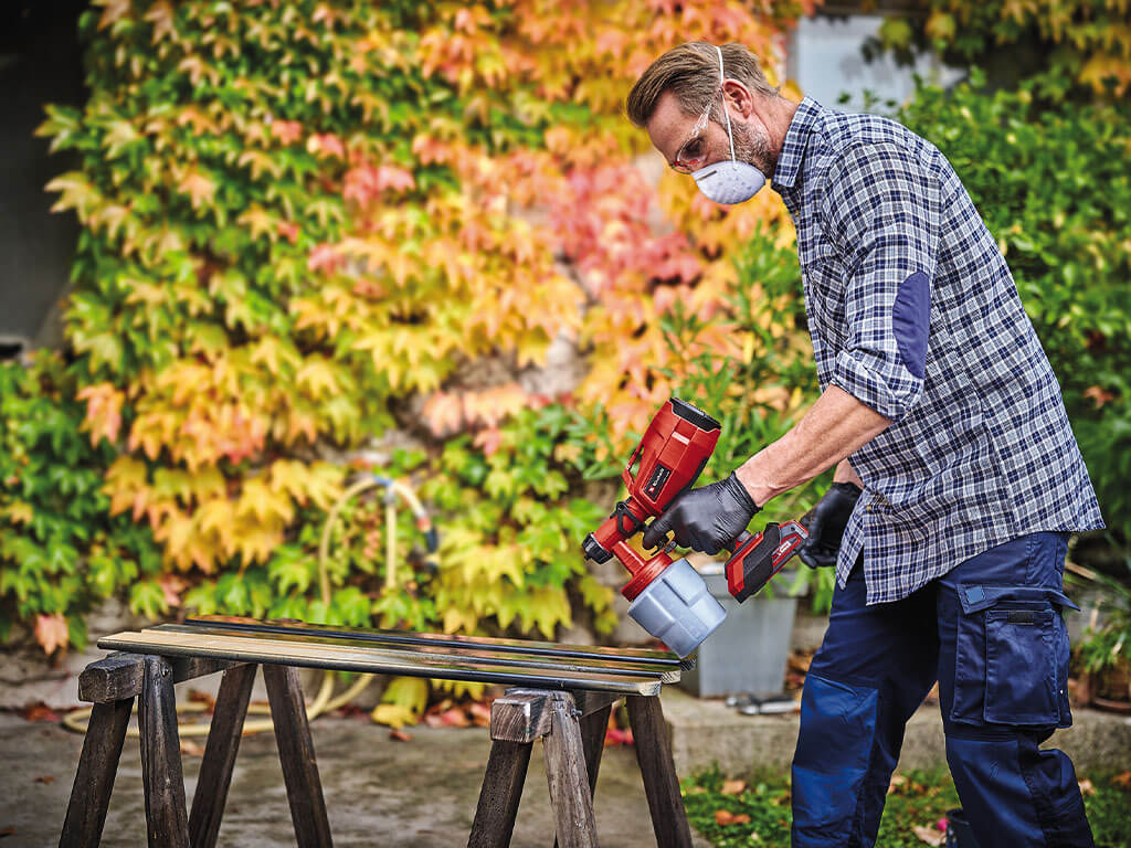 A man paints wooden slats with the cordless paint spray system from Einhell.