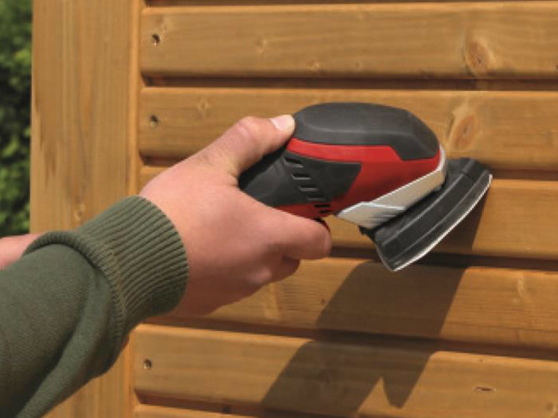 wooden wall is sanded with a triangular sander