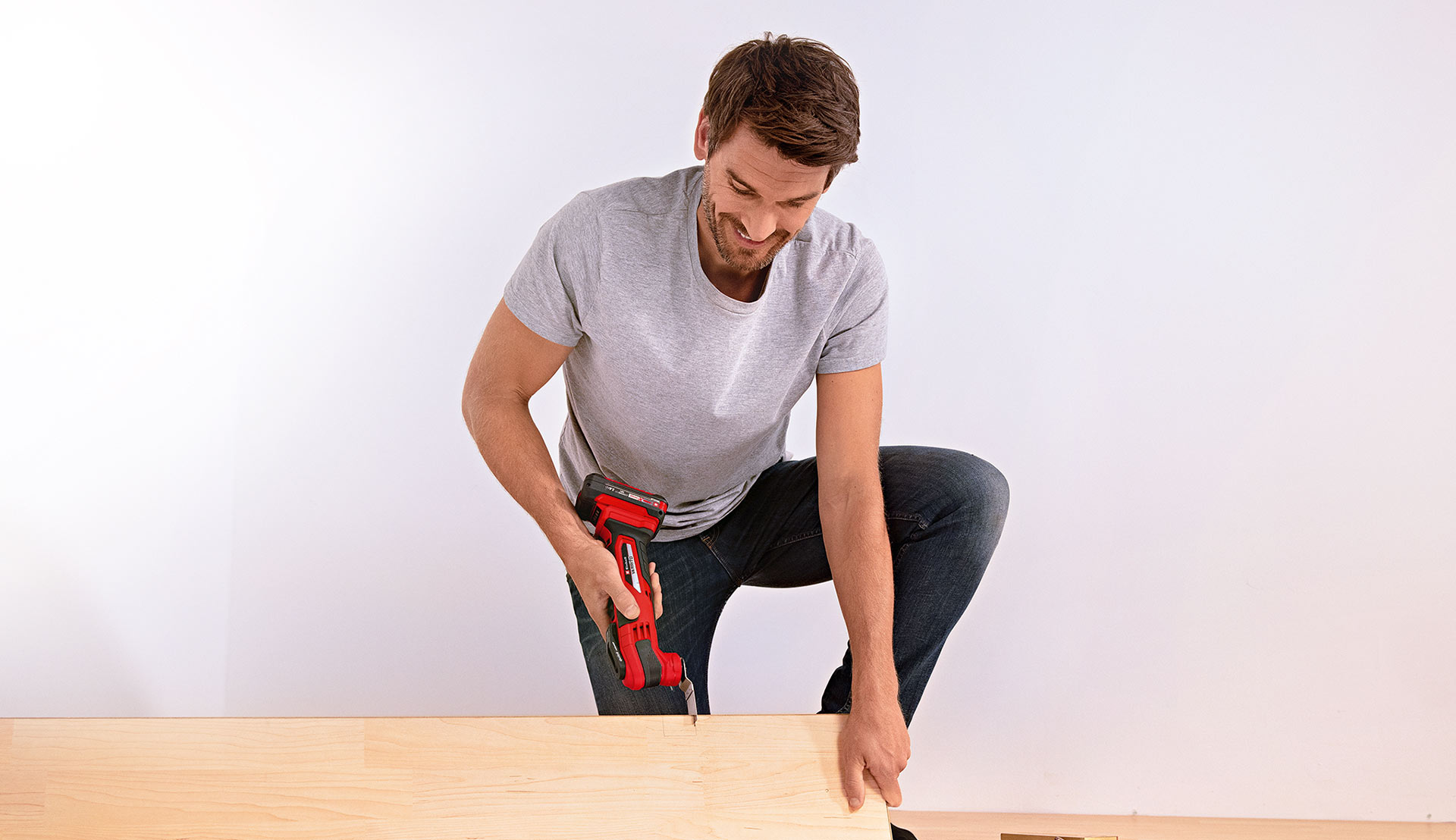 A man sawing into wood using a multifunctional tool.