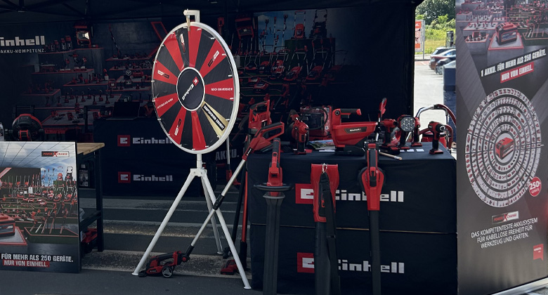 Ein Messestand von Einhell mit einem Glücksrad, ausgestellten Werkzeugen und Werbematerialien.