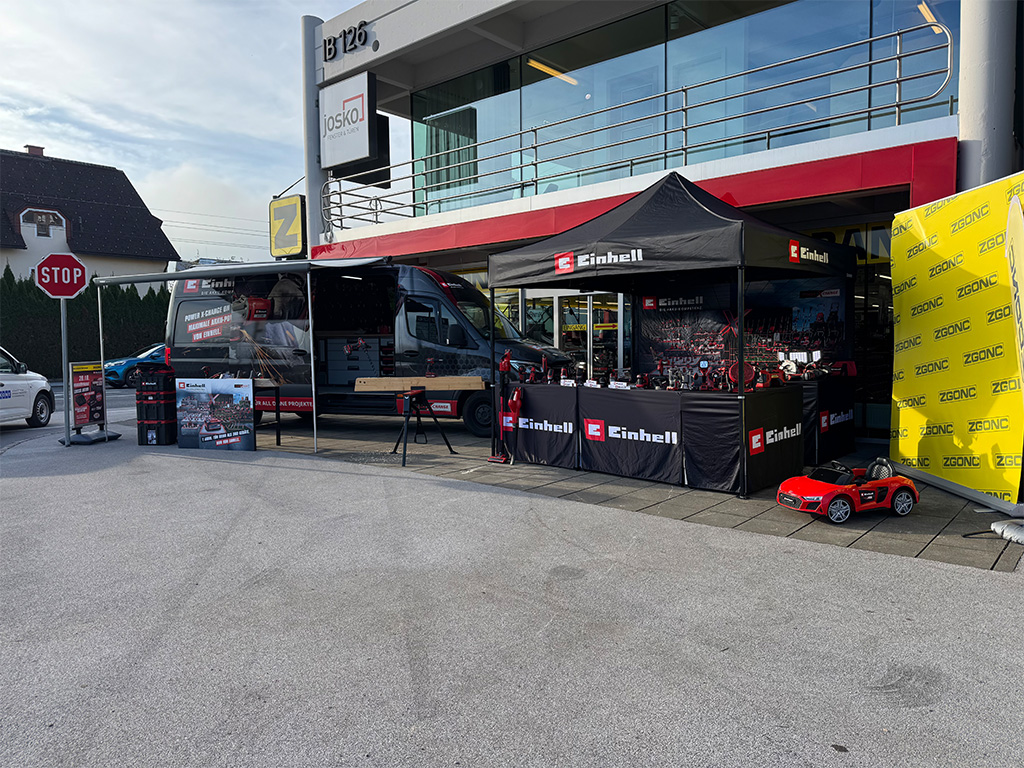 Einhell promotional tent set up outside a store, showcasing tools, banners, and a demonstration area.