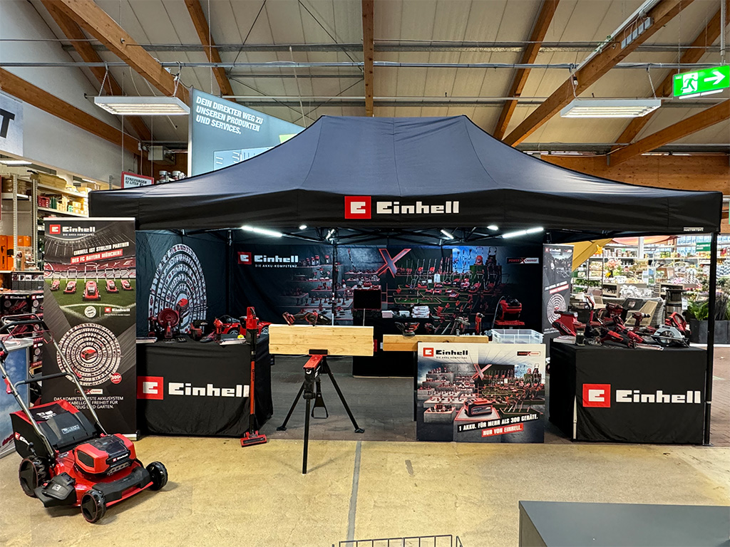 Indoor Einhell promotional booth showcasing tools and banners in a hardware store setting.