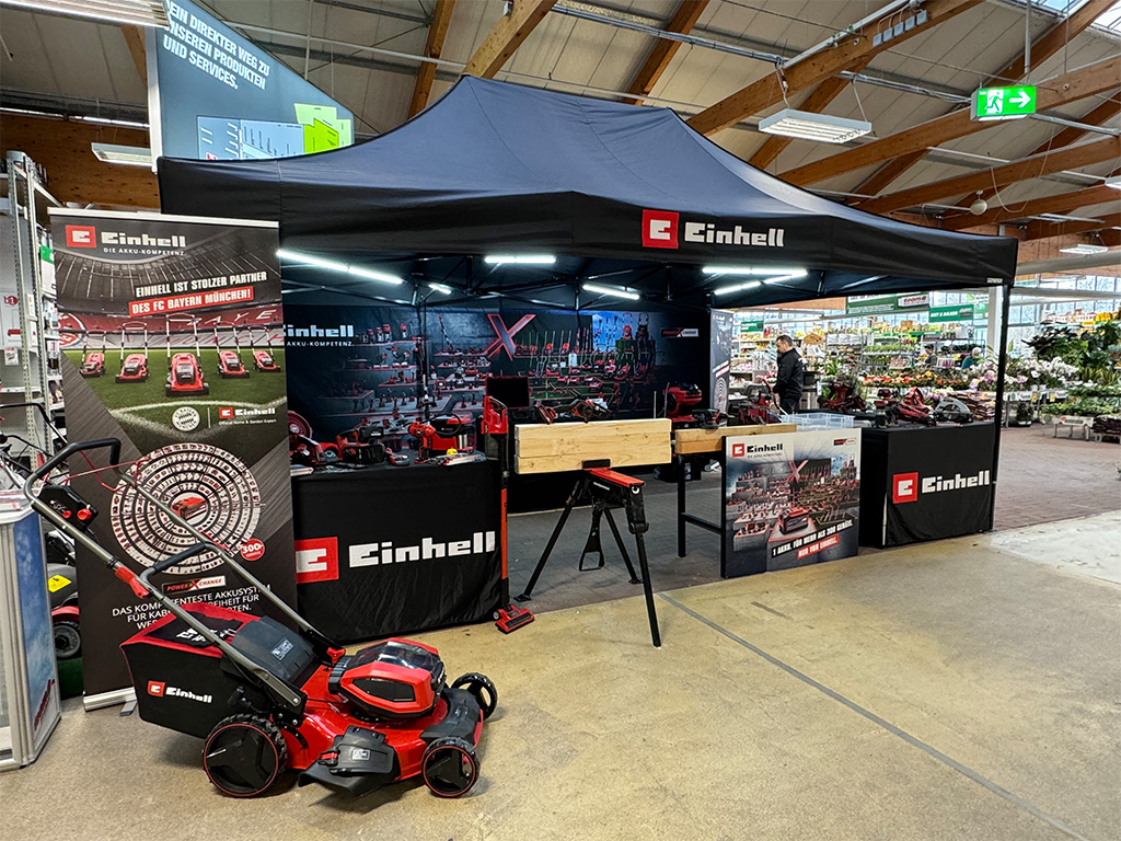 Indoor Einhell booth displaying tools and promotional materials, with a focus on garden equipment.