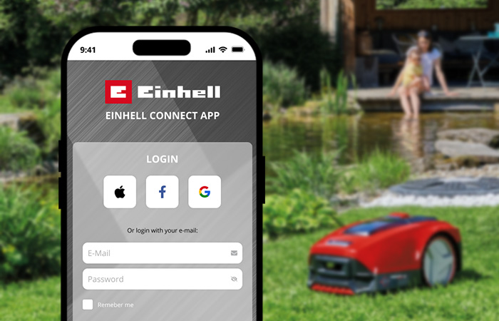 A smartphone displays the login screen of the Einhell Connect app against a garden background with a robotic lawn mower.